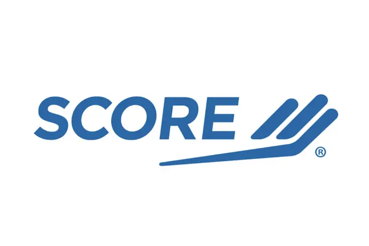 Blue italic “SCORE” word‑mark with wing‑shaped double tick—national nonprofit network of volunteer business mentors.