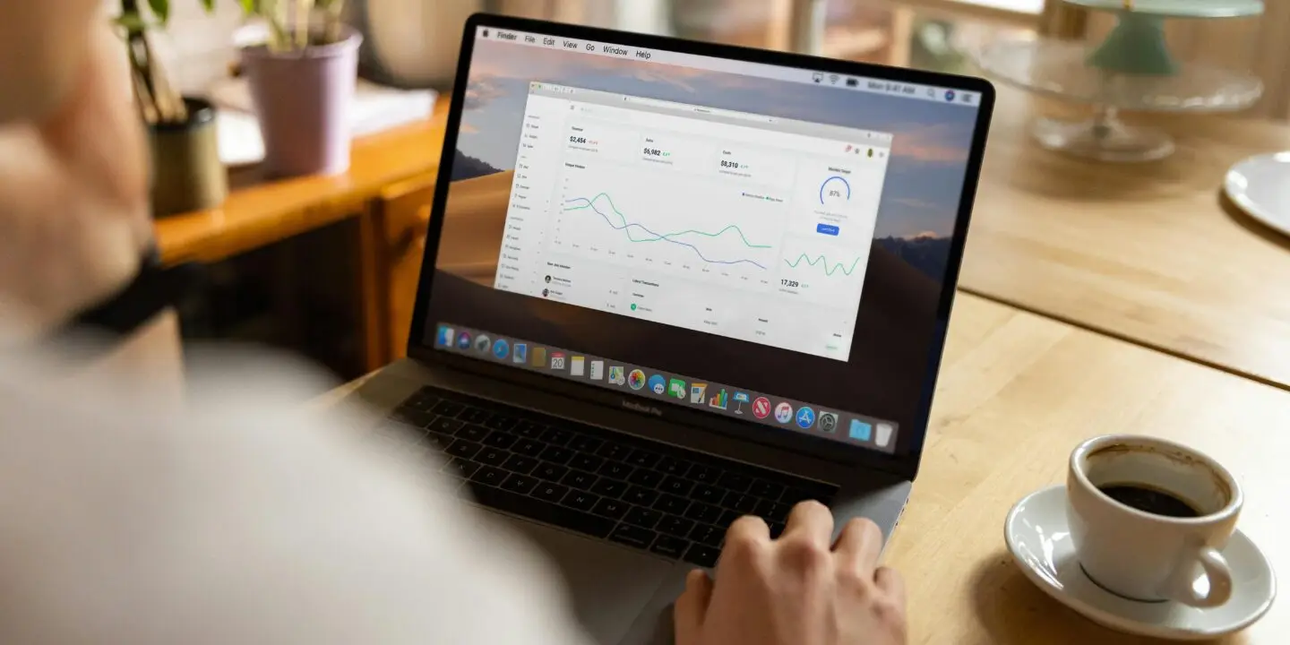 Design entrepreneur using a laptop for evaluating the marketing performance metrics on a data dashboard.