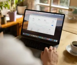 Design entrepreneur using a laptop for evaluating the marketing performance metrics on a data dashboard.