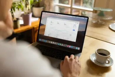 Design entrepreneur using a laptop for evaluating the marketing performance metrics on a data dashboard.
