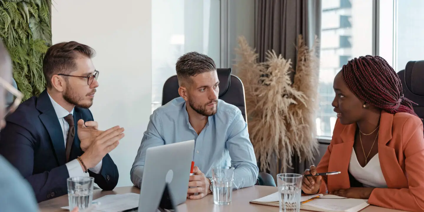 Diverse business team in a formal boardroom discussing strategy during a design entrepreneurship meeting.