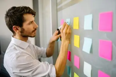 Focused design entrepreneur writing on colorful sticky notes during a business goal setting session.