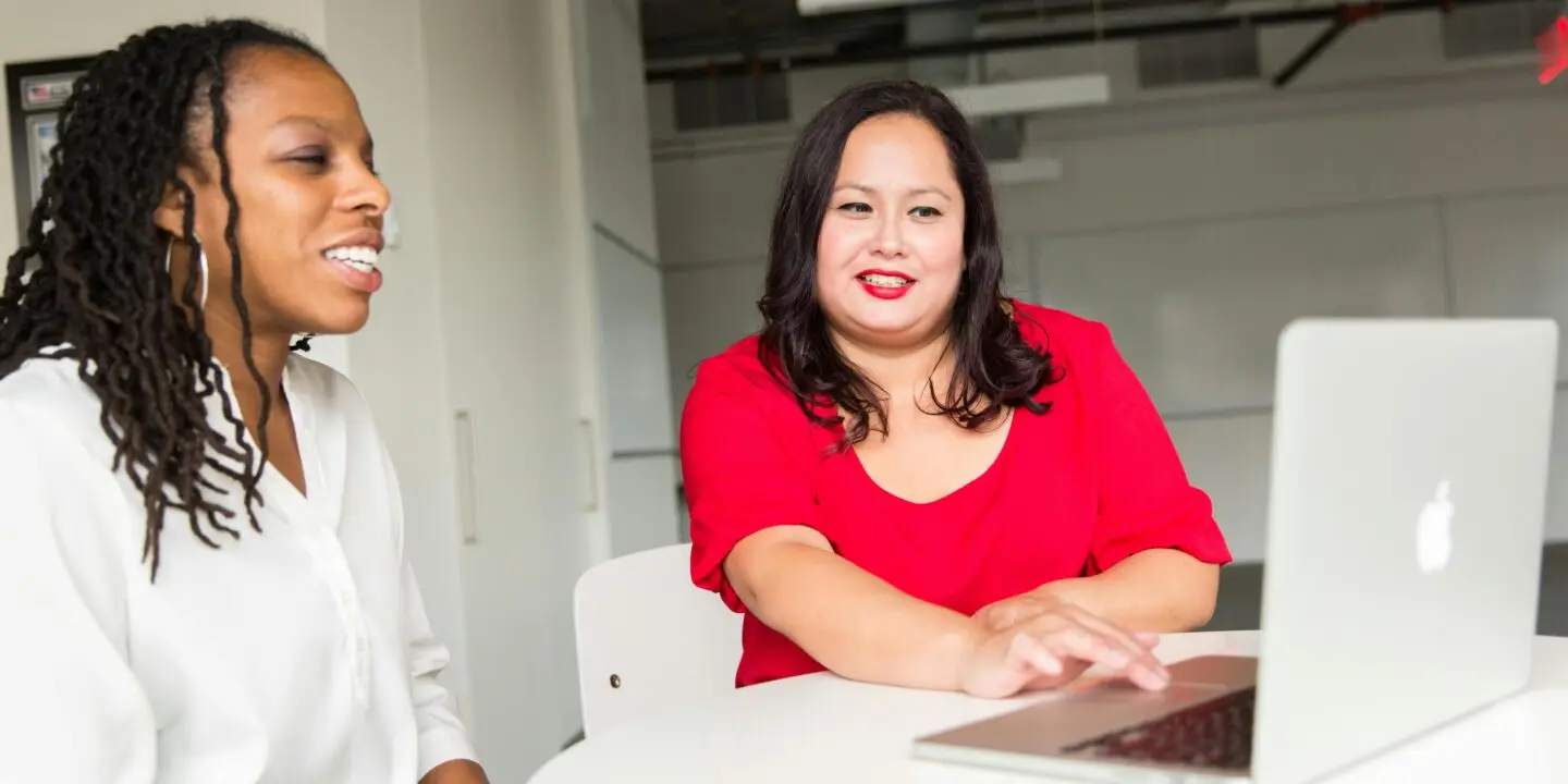 Design businesswomen discussing strategy with client while using a laptop in a modern design office