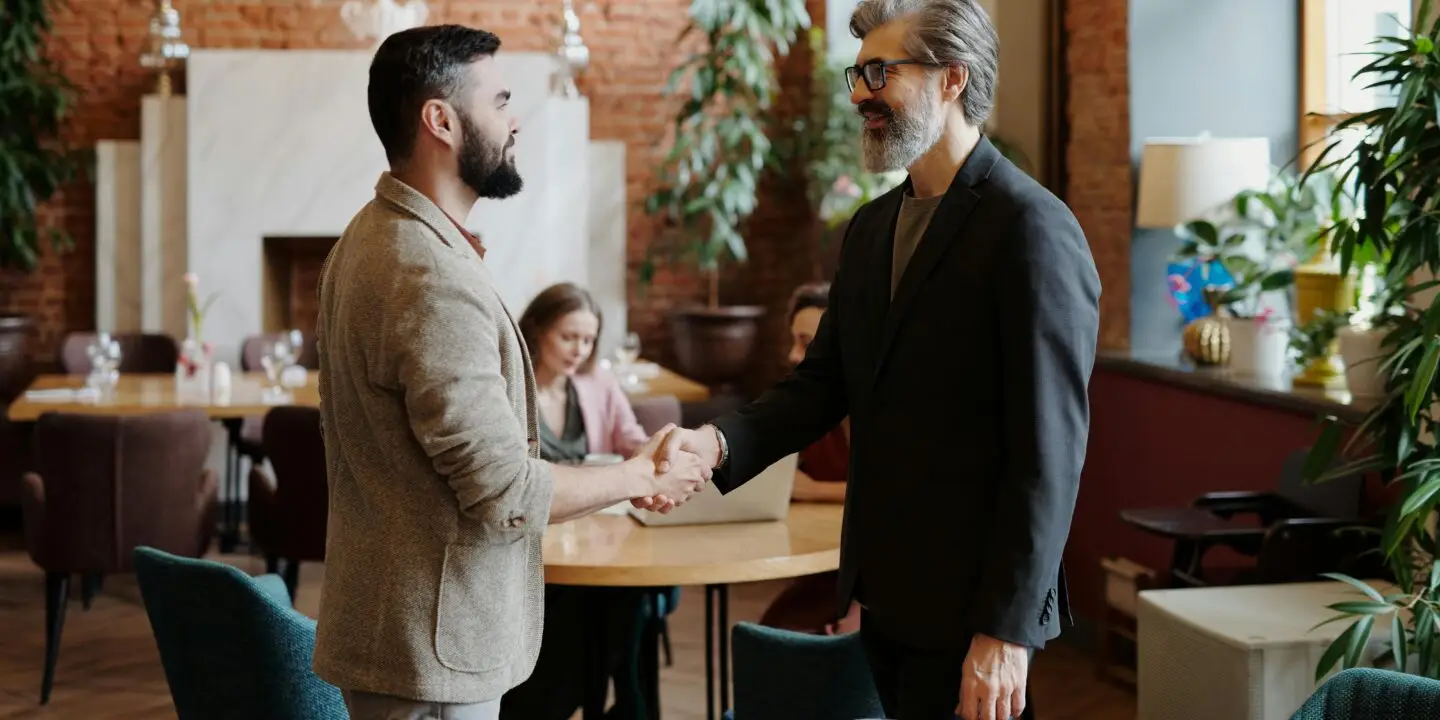 Design businessmen shaking hands with client in a modern office during a negotiating meeting.
