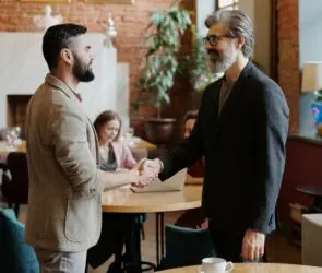 Design businessmen shaking hands with client in a modern office during a negotiating meeting.
