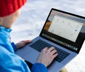 Design entrepreneur person in a red beanie using a laptop outdoors to track business social media analytics on a dashboard.