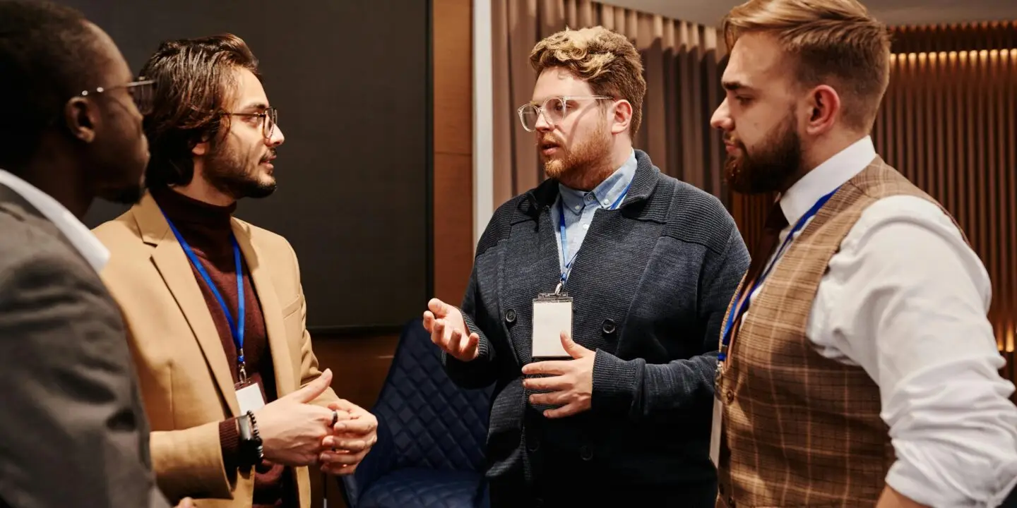 Group of male design entrepreneurs networking and discussing ideas for partnership at a business conference.