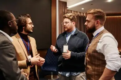 Group of male design entrepreneurs networking and discussing ideas for partnership at a business conference.