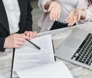 Design Entrepreneur and client reviewing design services proposal documents beside a laptop.