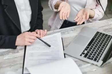 Design Entrepreneur and client reviewing design services proposal documents beside a laptop.