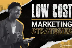 Smiling design entrepreneur holding a digital tablet and stylus, with bold text that reads “Low Cost Marketing Strategies.”