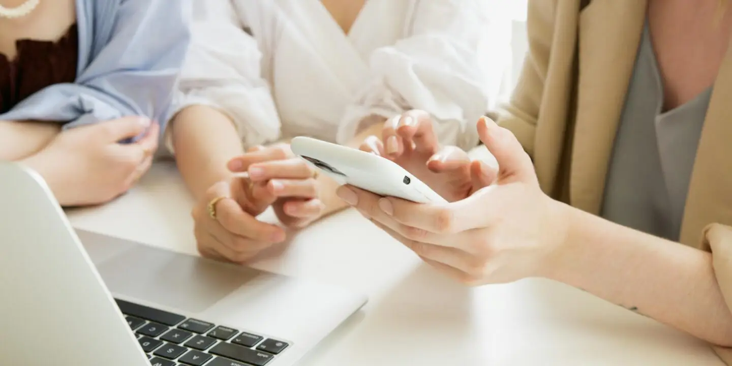 Business owners reviewing financial data on smartphone beside laptop.