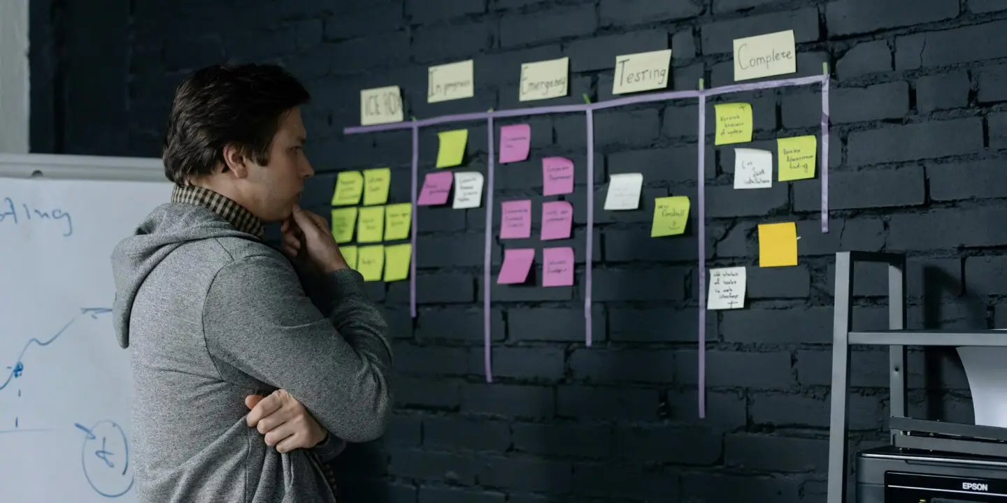 Freelancer planning workflow on a wall covered with sticky notes, organizing project stages for productivity and progress tracking.