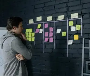 Freelancer planning workflow on a wall covered with sticky notes, organizing project stages for productivity and progress tracking.
