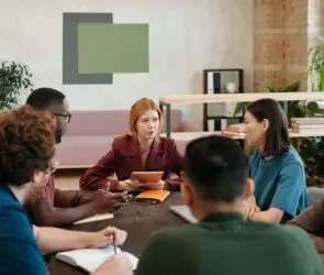 Diverse group of creative professionals having a business strategy meeting in a modern studio, discussing ways to scale and grow a design business.