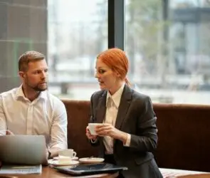 Designer and client working on project planning and cost estimation at a laptop in a home workspace.
