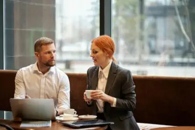 Designer and client working on project planning and cost estimation at a laptop in a home workspace.