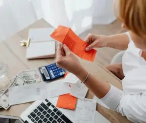 Designer reviewing receipts, cash, and calculator at desk.
