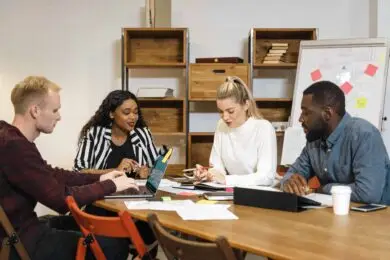 Diverse team of creative professionals collaborating around a meeting table, discussing leadership and business strategies for a design startup.