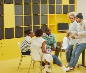 Creative team collaborating in a modern workspace with yellow wall panels.