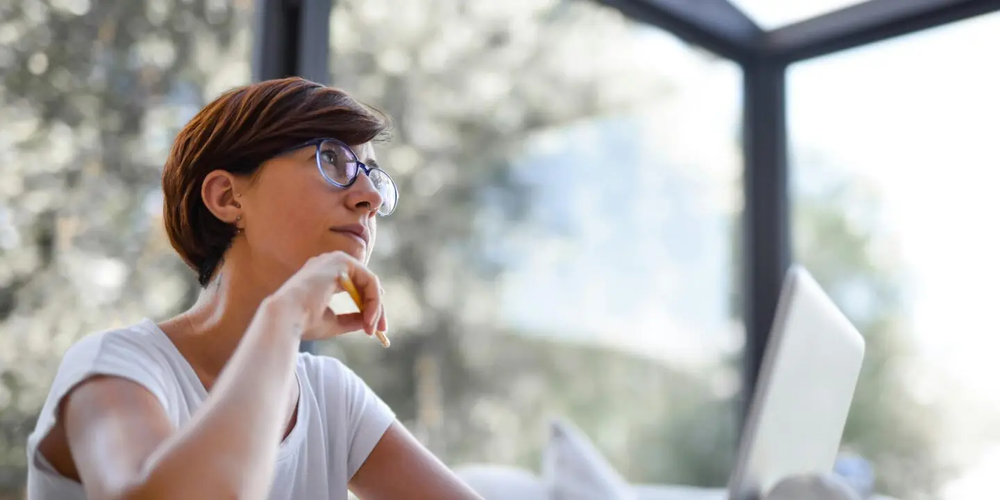 Designer thinking while working on a laptop in a modern workspace.