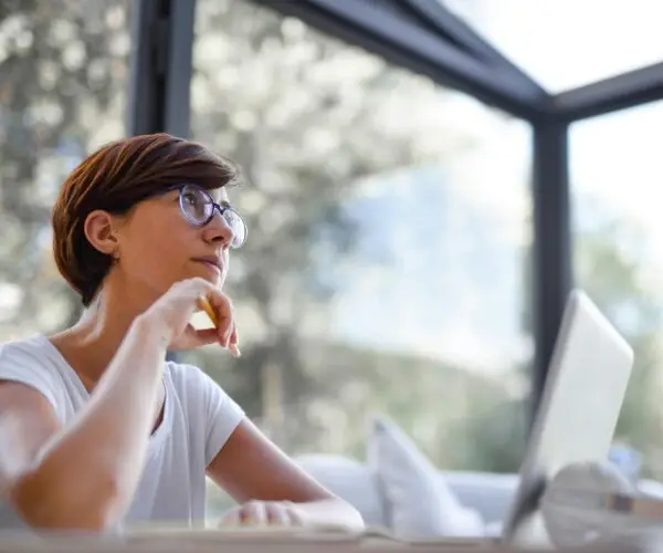 Designer thinking while working on a laptop in a modern workspace.