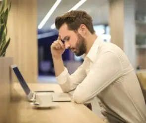 Designer thinking while working on laptop strategy.