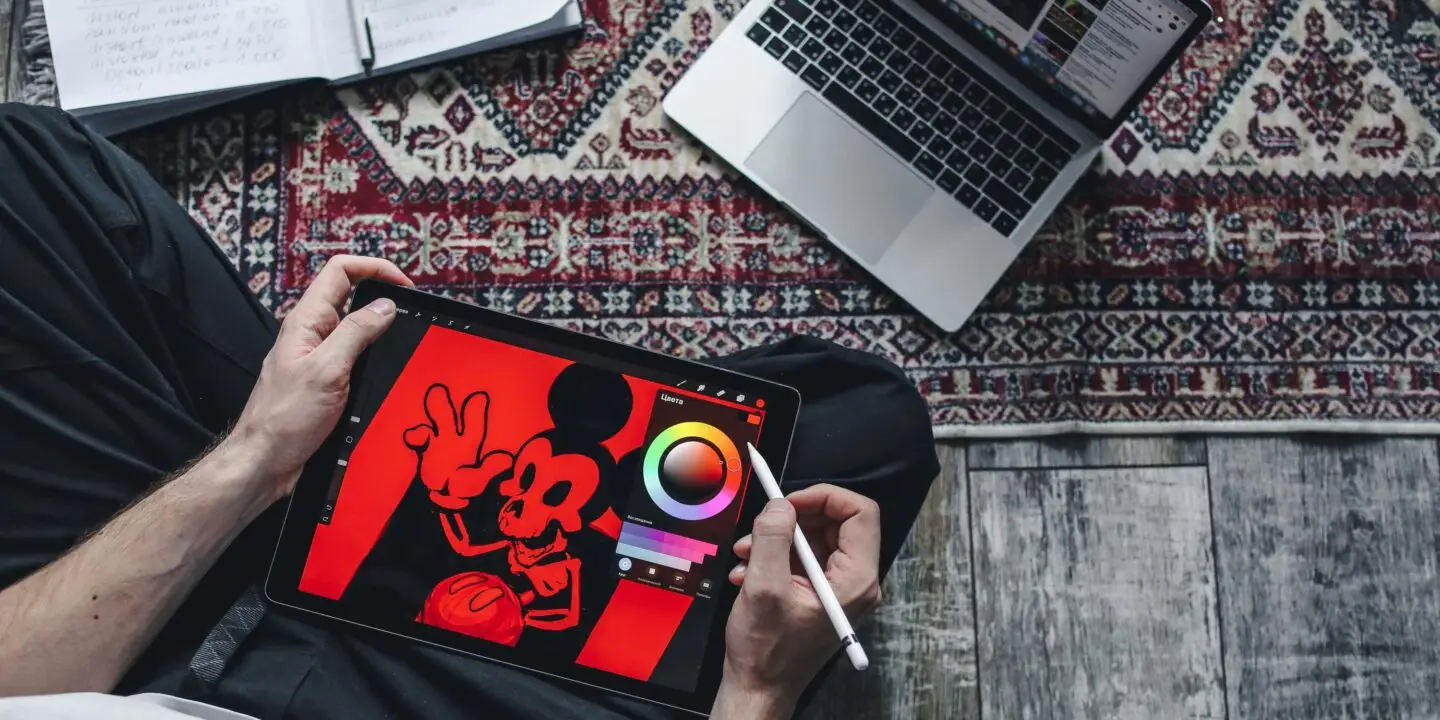 Designer creating digital illustration on tablet workspace.