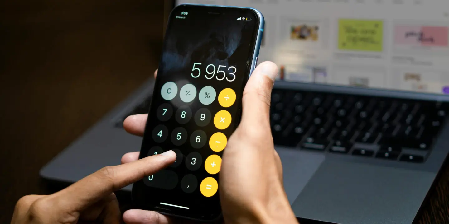 Person using smartphone calculator to determine pricing and profit margins for digital products.
