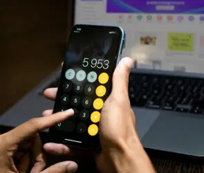 Person using smartphone calculator to determine pricing and profit margins for digital products.