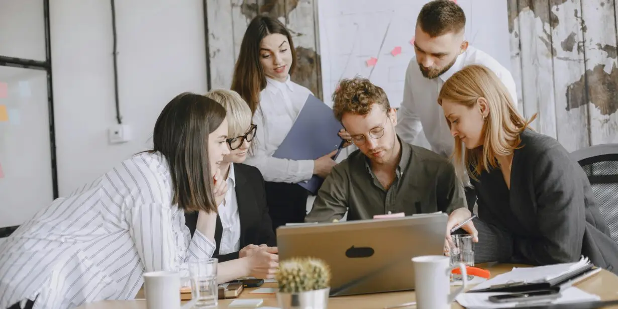 Creative team reviewing project work together on a laptop in an office setting.