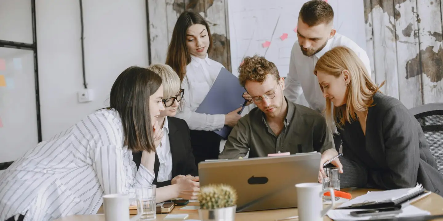 Creative team reviewing project work together on a laptop in an office setting.