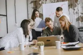 Creative team reviewing project work together on a laptop in an office setting.