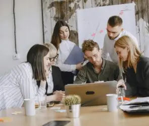 Creative team reviewing project work together on a laptop in an office setting.