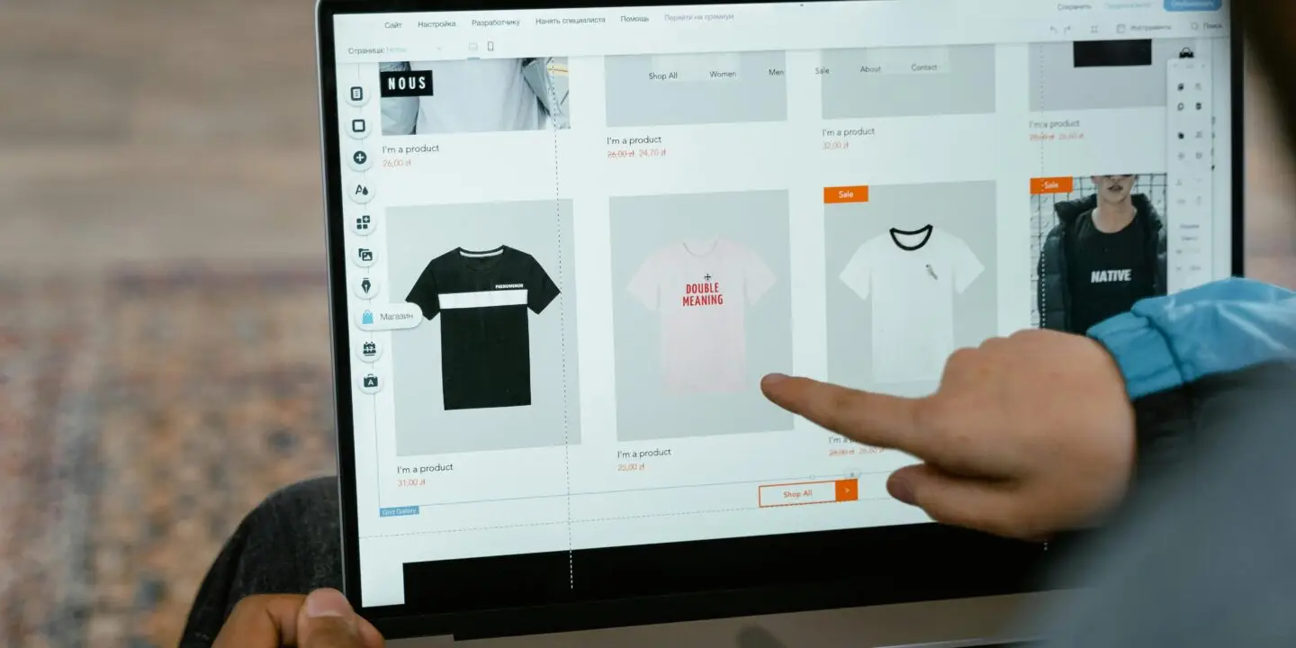 Person browsing custom t-shirt products on an online store using a laptop.