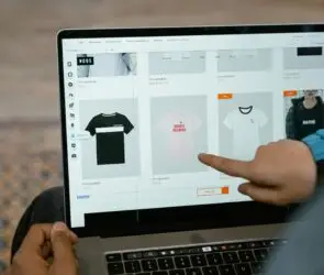 Person browsing custom t-shirt products on an online store using a laptop.