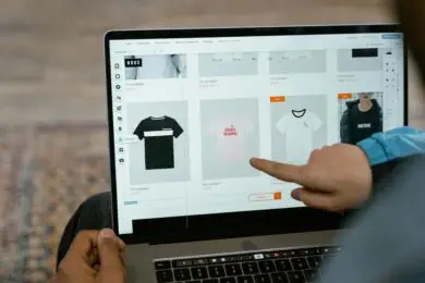 Person browsing custom t-shirt products on an online store using a laptop.
