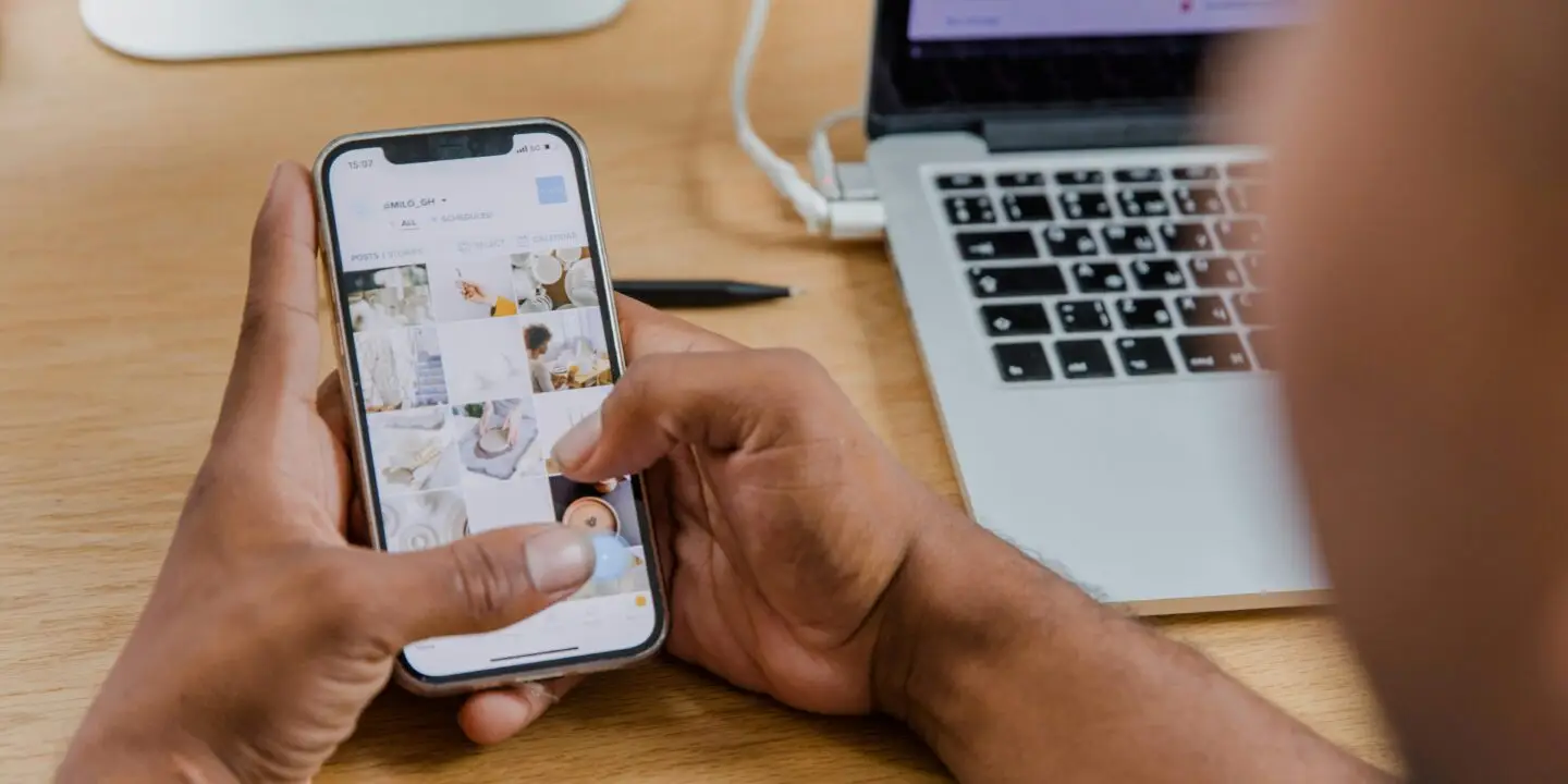 Entrepreneur managing product images and content on a smartphone for an online design business.