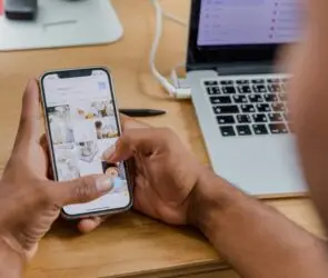 Entrepreneur managing product images and content on a smartphone for an online design business.