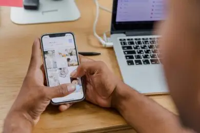 Entrepreneur managing product images and content on a smartphone for an online design business.