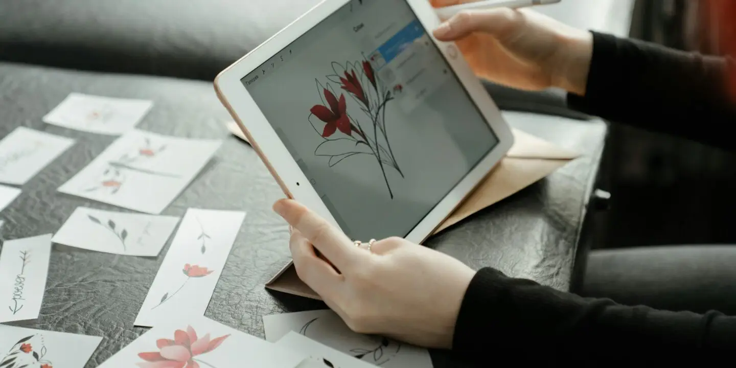 Designer using a tablet to create floral illustration artwork and digital assets for online product sales.