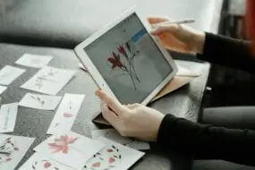 Designer using a tablet to create floral illustration artwork and digital assets for online product sales.