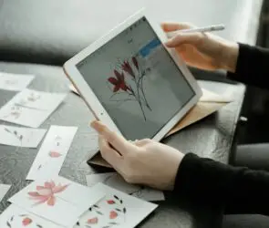 Designer using a tablet to create floral illustration artwork and digital assets for online product sales.