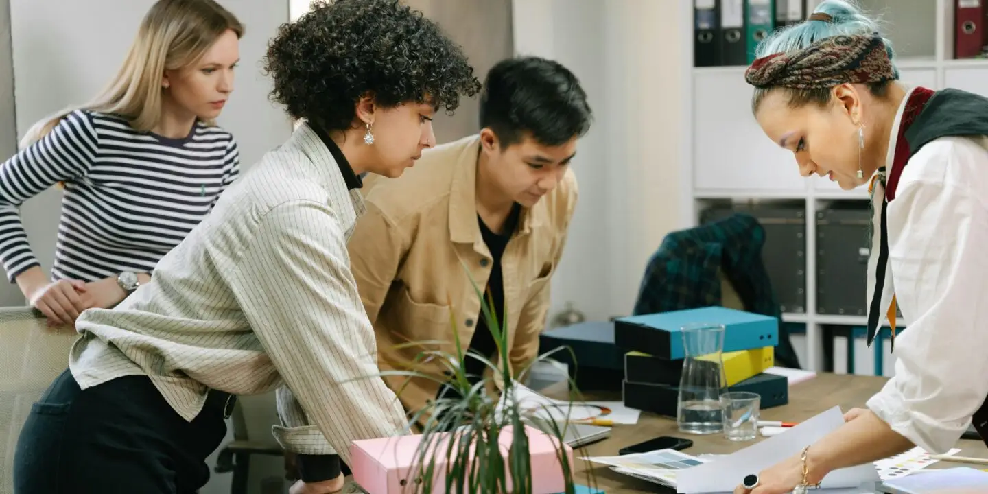 Group of professionals reviewing documents and collaborating around a table in an office workspace.