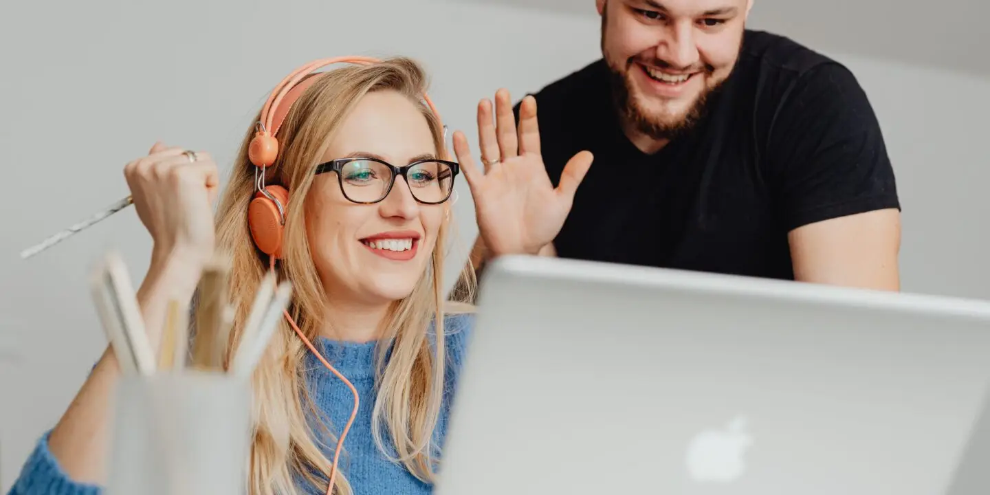 Two designers smiling and waving during an online meeting.
