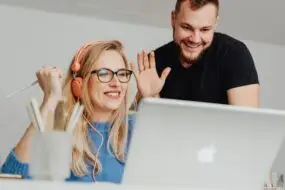 Two designers smiling and waving during an online meeting.