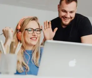 Two designers smiling and waving during an online meeting.