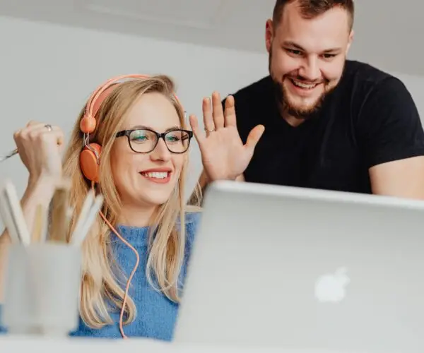 Two designers smiling and waving during an online meeting.