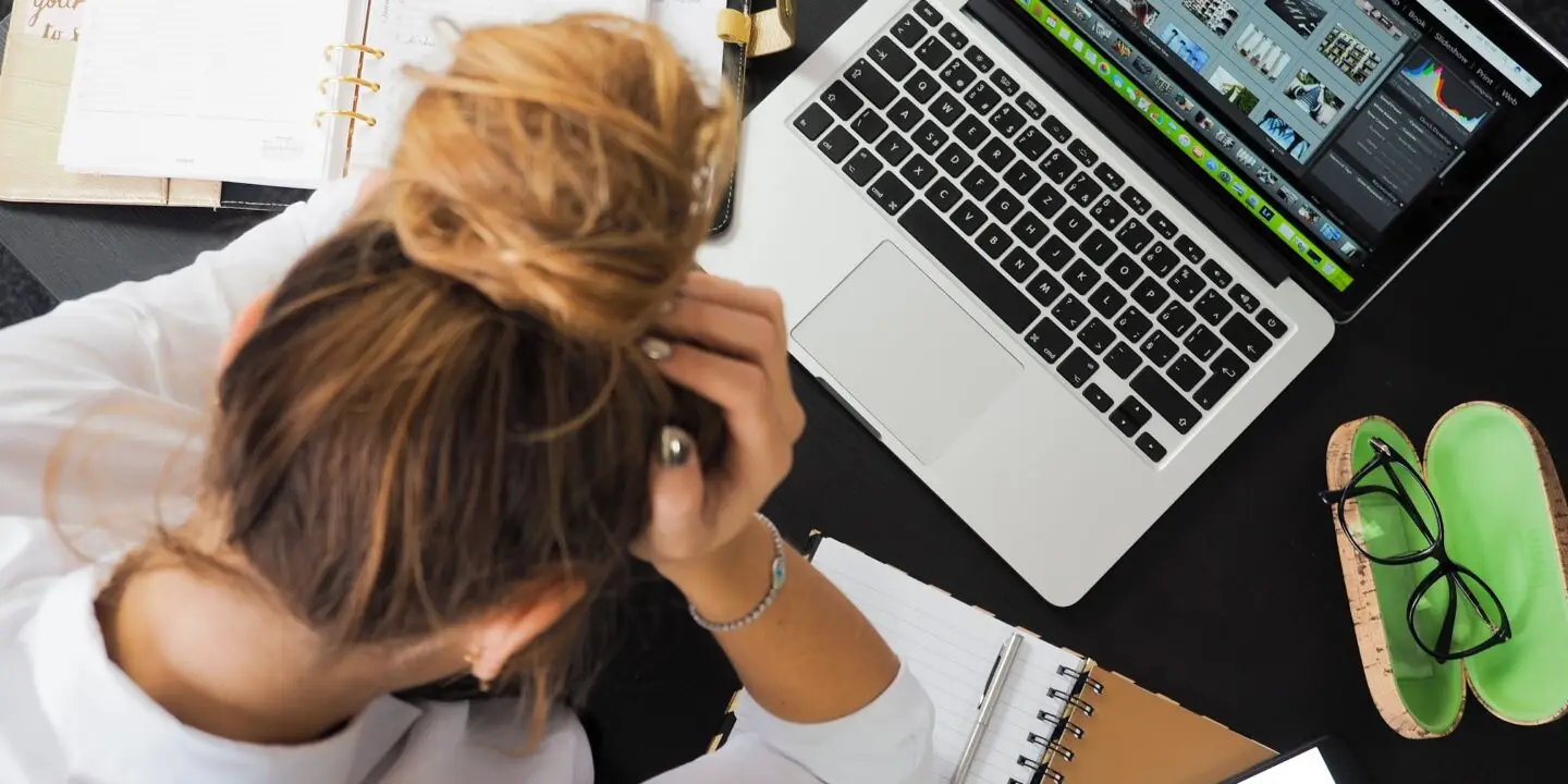 Overwhelmed designer managing multiple projects, schedules, and creative files at a cluttered workspace.