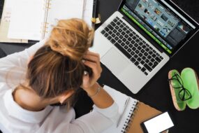 Overwhelmed designer managing multiple projects, schedules, and creative files at a cluttered workspace.